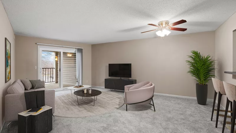 Modern living room with a light gray sofa, TV, pink armchair, and balcony access. Neutral colors and a gray carpet.